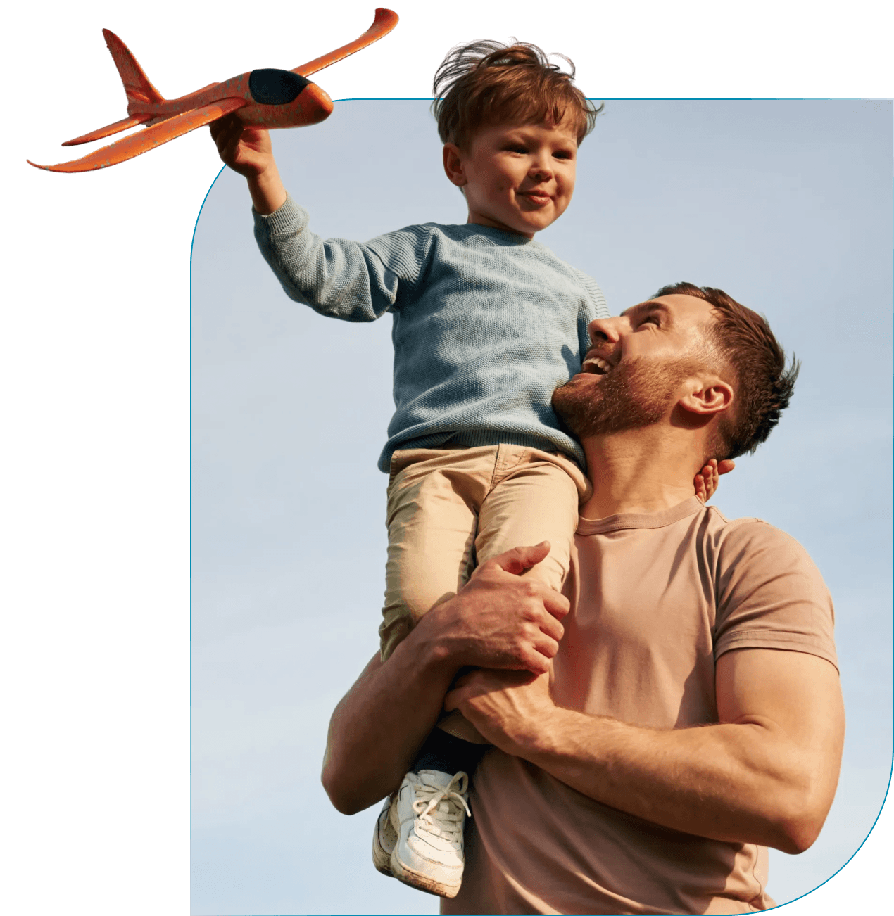 Father holding son on his shoulders outdoors, son holding a toy airplane